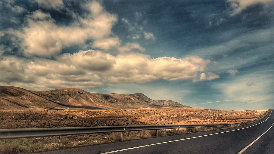 road beside desert under clear blue skies, volcano, clouds, fuerteventura