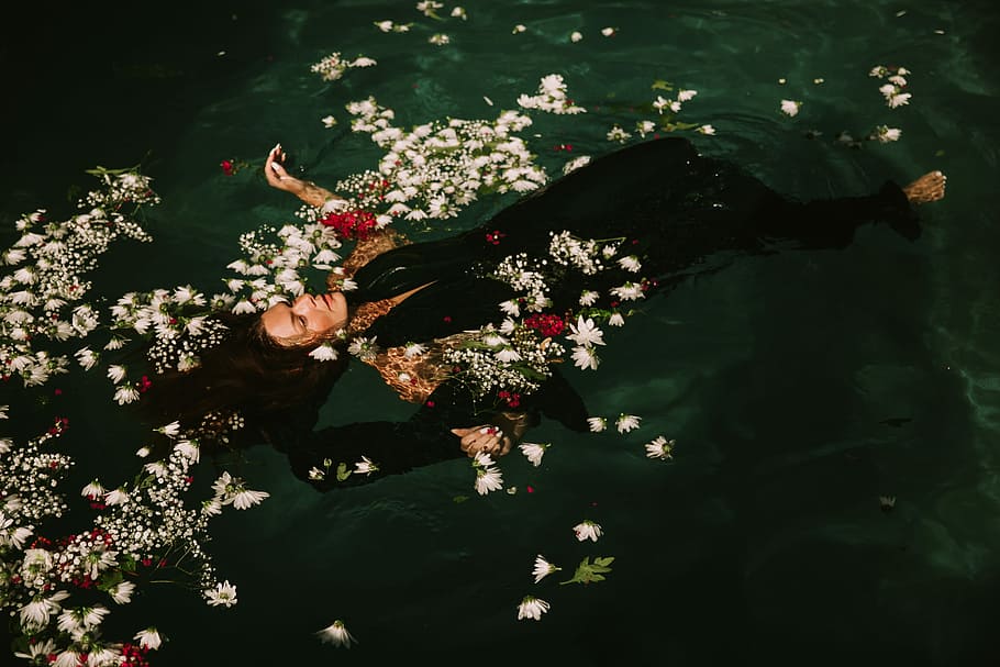 woman wearing black suit floats on the water, woman wearing black sleeveless top floating on water with white flowers