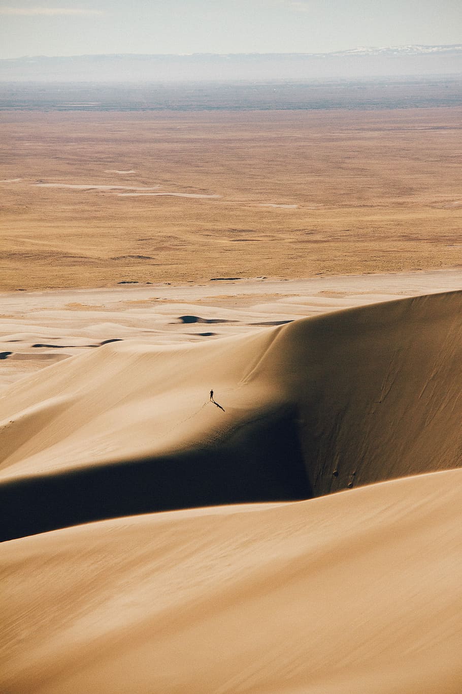 brown desert under white sky during daytime, man walking in the middle of desert HD wallpaper