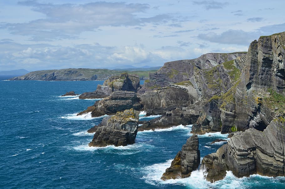 aerial photography of brown rock formations and seawaves at daytime HD wallpaper