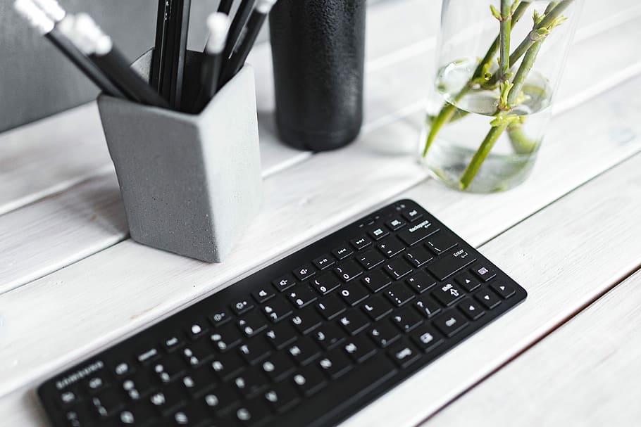 Black keyboard with pencils on a white table, bottle, plant, computer HD wallpaper