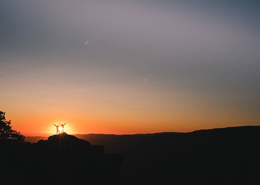 silhouette of couple on cliff during golden hour, silhouette of two person standing on rock formation with golden hours sun background HD wallpaper