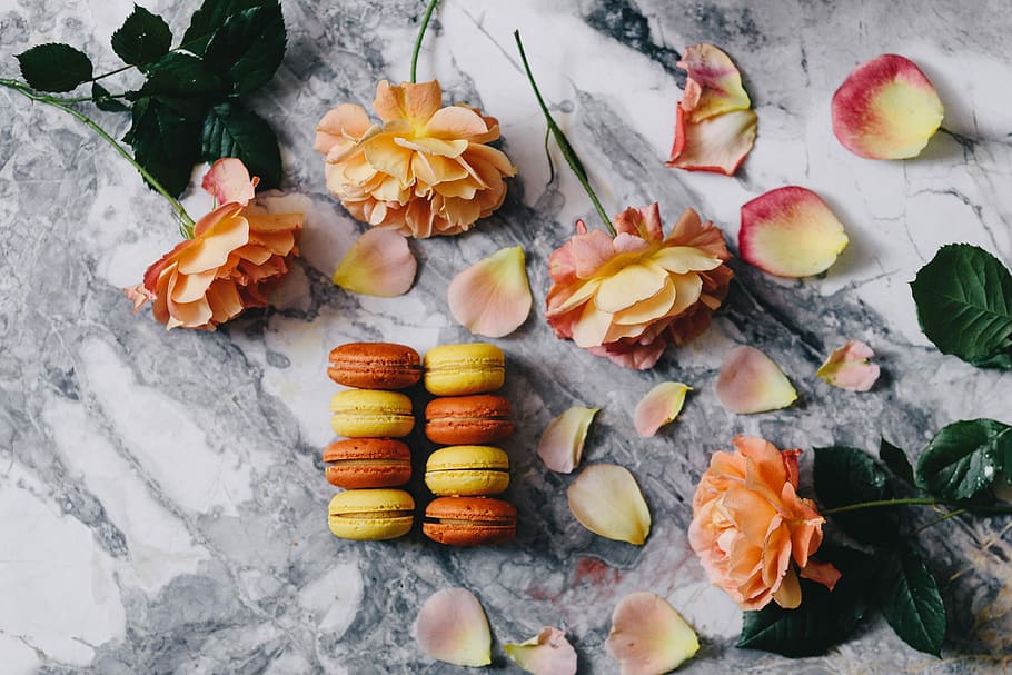 Overhead view of macarons on a marble slab, roses, yellow, sweet