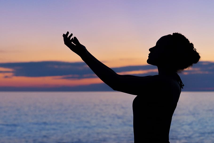 silhouette of woman raising her right hand, silhouette of a woman raising hands
