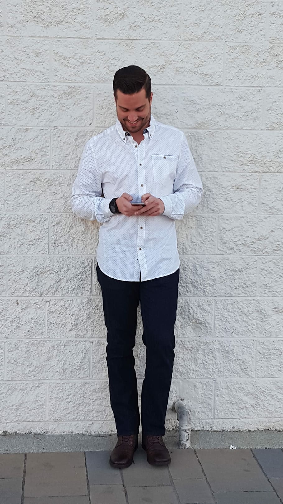 man using smartphone while standing against the white wall HD wallpaper