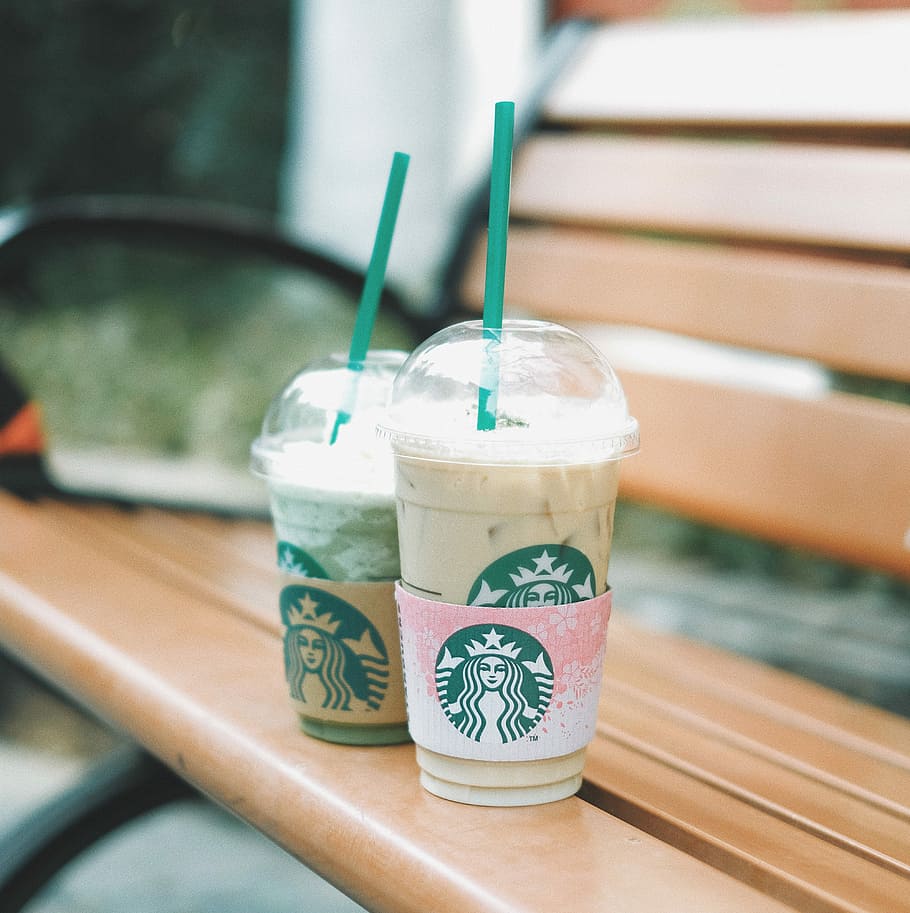 two Starbucks cups on bench, two Starbucks plastic cups, drink