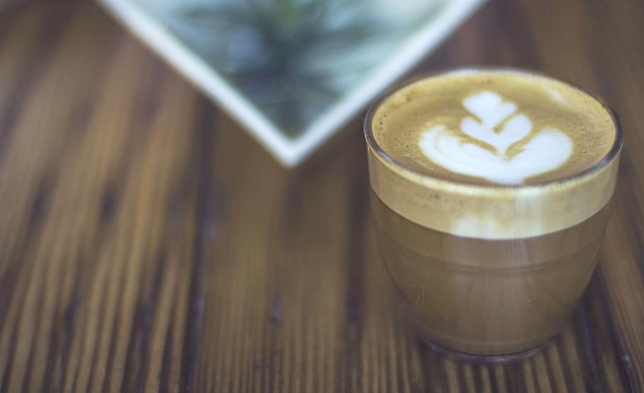macro photography of latte in drinking glass, cappuccino on brown wooden board
