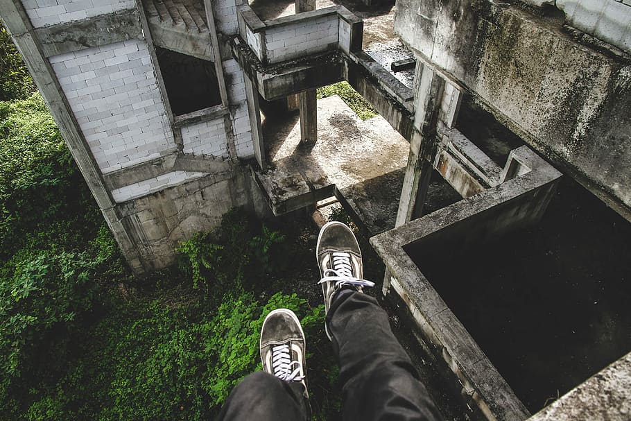 human wearing black pants and pair of gray Vans Old Skool sitting on cliff of abandoned concrete house, HD wallpaper