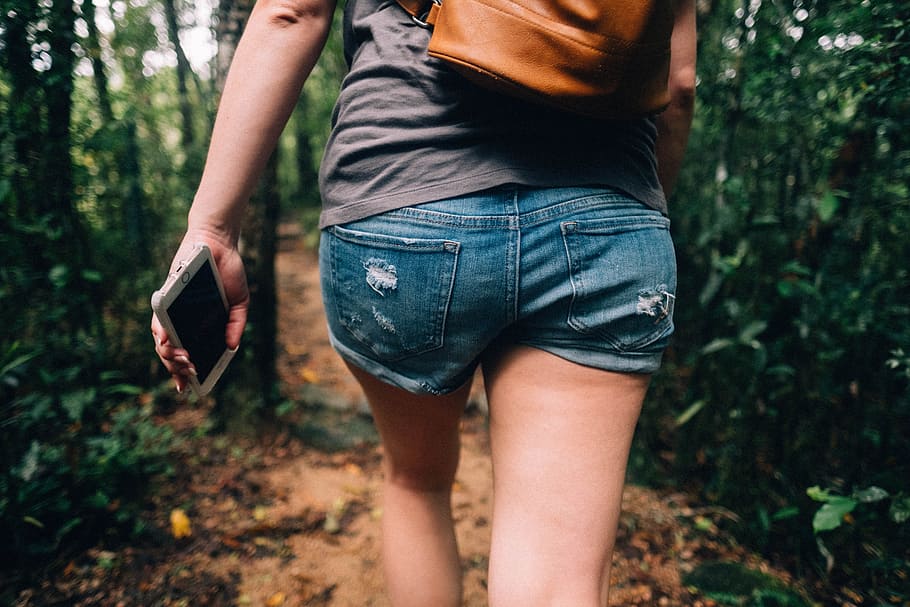 woman holding phone walking toward trees, close up of human wearing shorts walking hallway HD wallpaper
