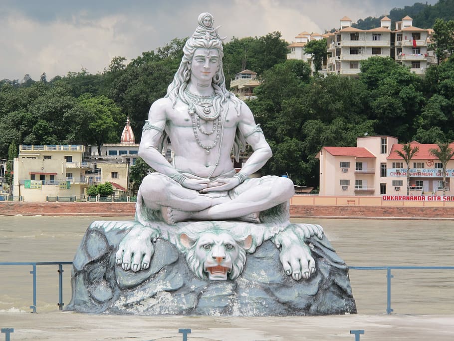 statue of Hindu Deity sitting on white tiger near river, India