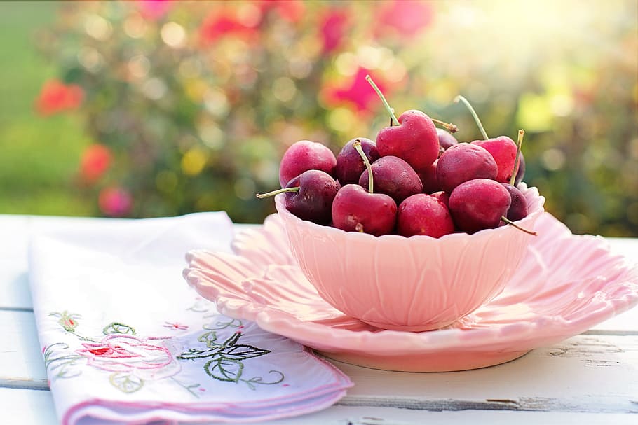 pink bowl of red cherry fruits beside pink floral cloth, saucer, HD wallpaper