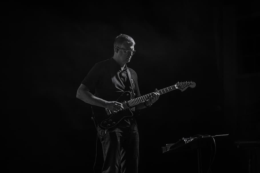man playing guitar, grayscale photo of man playing electric guitar