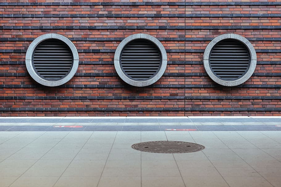 three round black tunnel on brown concrete brick building at daytime, three gray vents