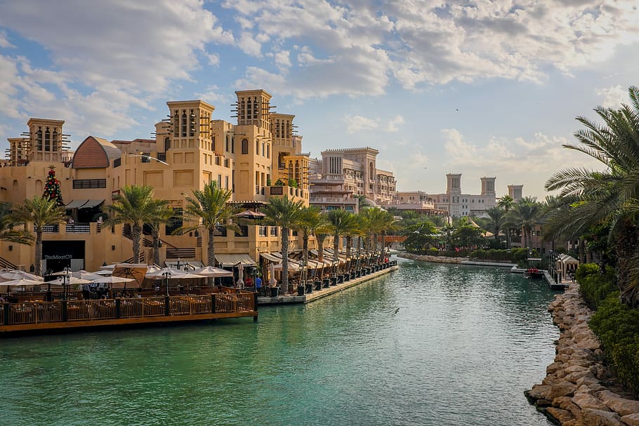 beige concrete building under white clouds, body of water near building during daytime HD wallpaper