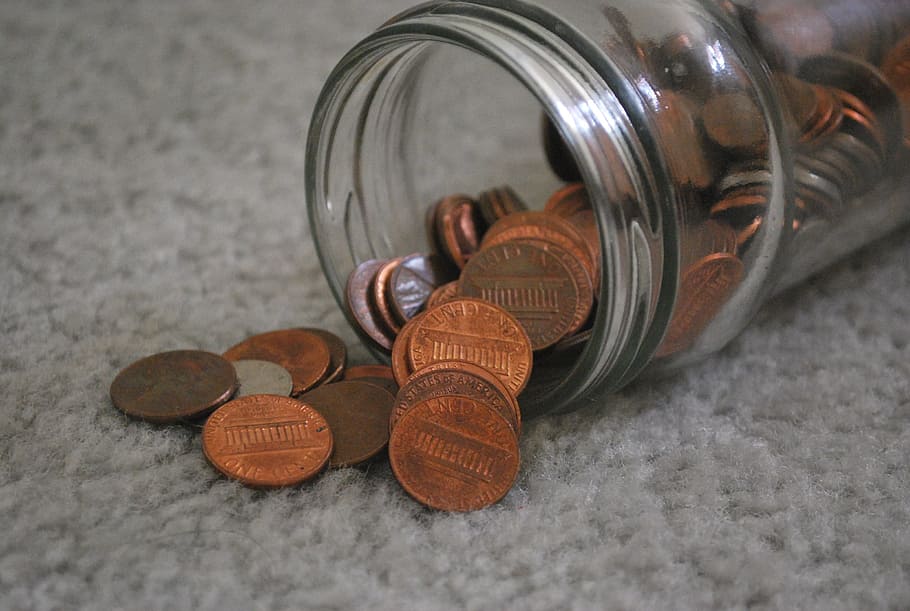 bronze coins in clear glass jar, pennies, money, spill, spilled