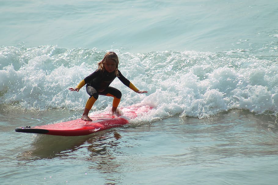 girl riding red surfboard in the ocean during daytime, child HD wallpaper
