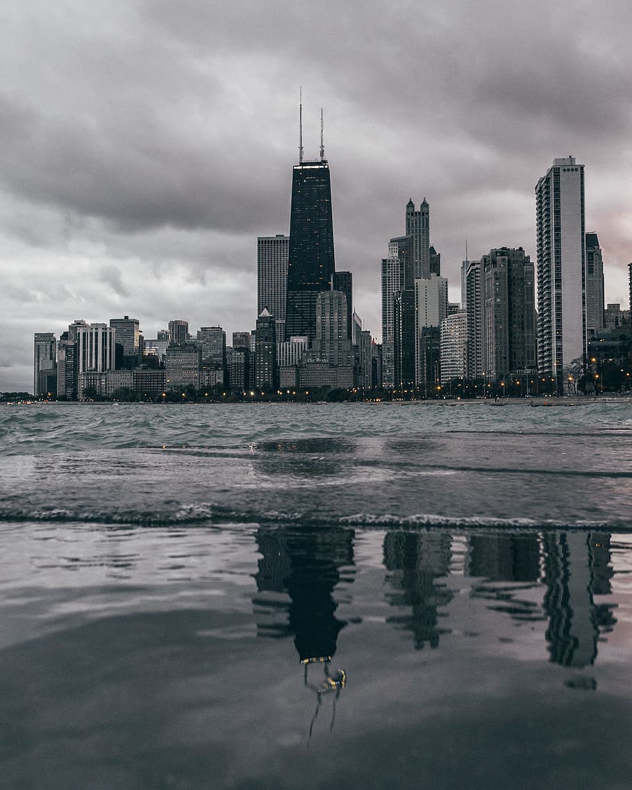 calm body of water near concrete buildings at daytime, grayscale photography of city building near body of water HD wallpaper