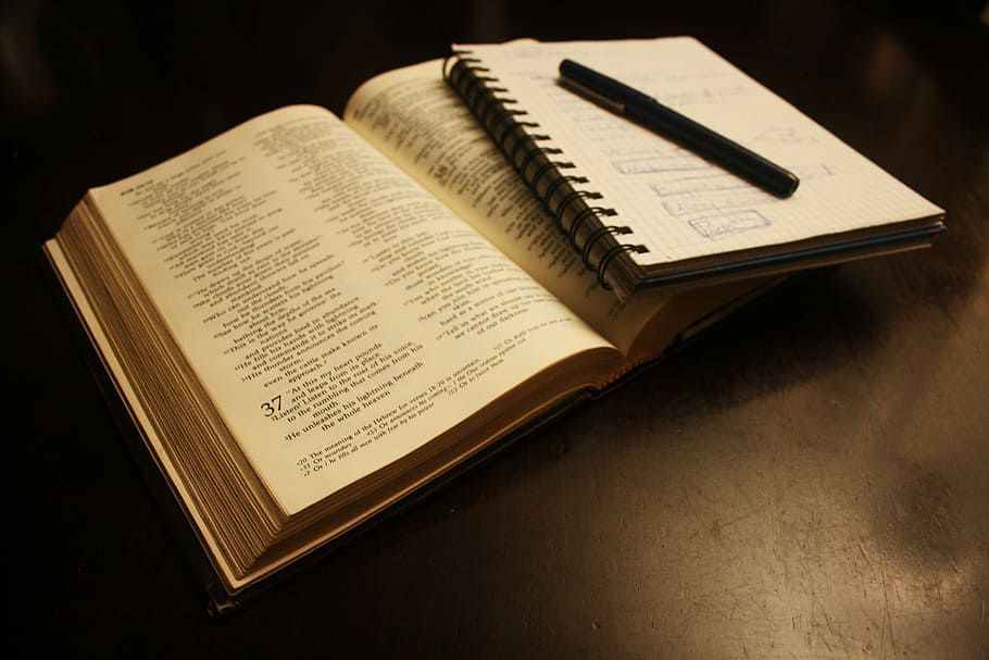 black ballpoint pen on top of white spiral notebook, bible, text