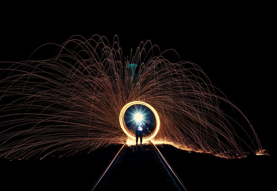 steel wool photography of person standing on train rails during daytime HD wallpaper