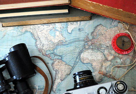 high-angle photo of DSLR camera, binoculars, compass, and books on top of map HD wallpaper