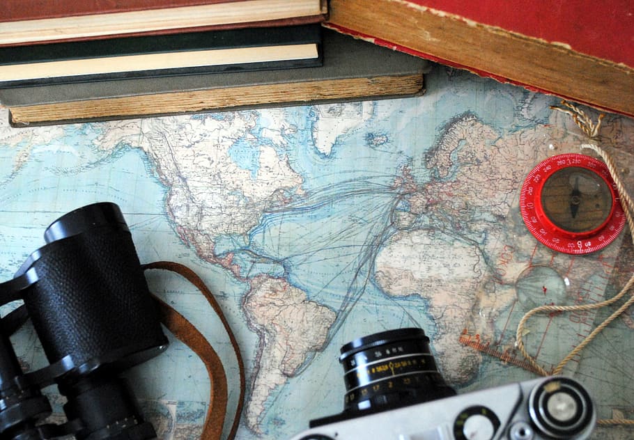 high-angle photo of DSLR camera, binoculars, compass, and books on top of map HD wallpaper