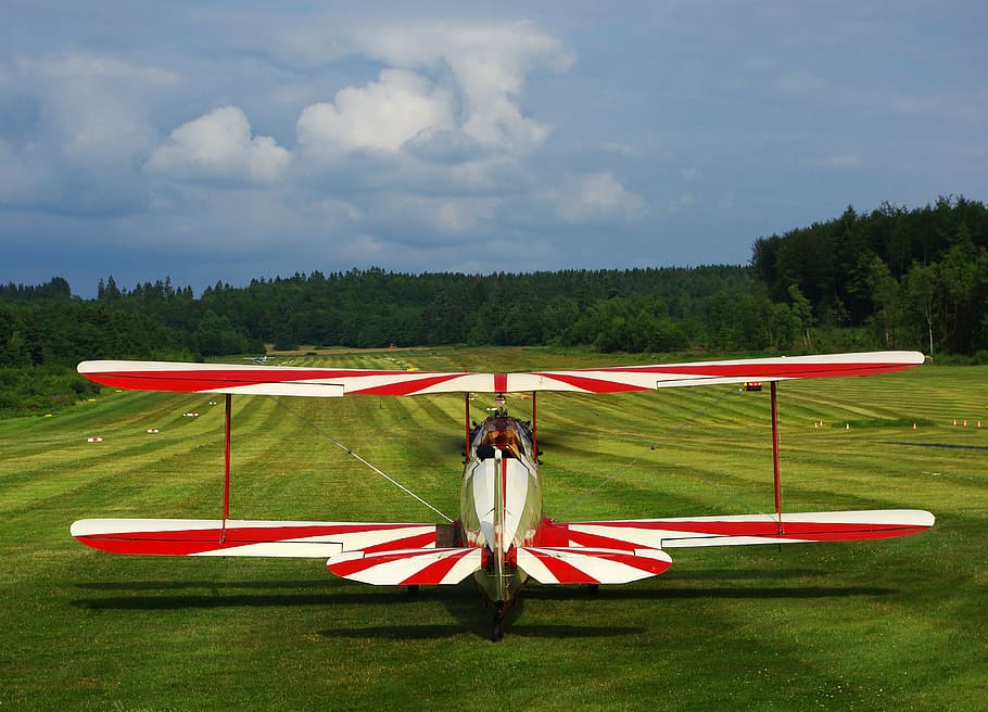 red and white striped biplane on ground, sport aircraft, runway