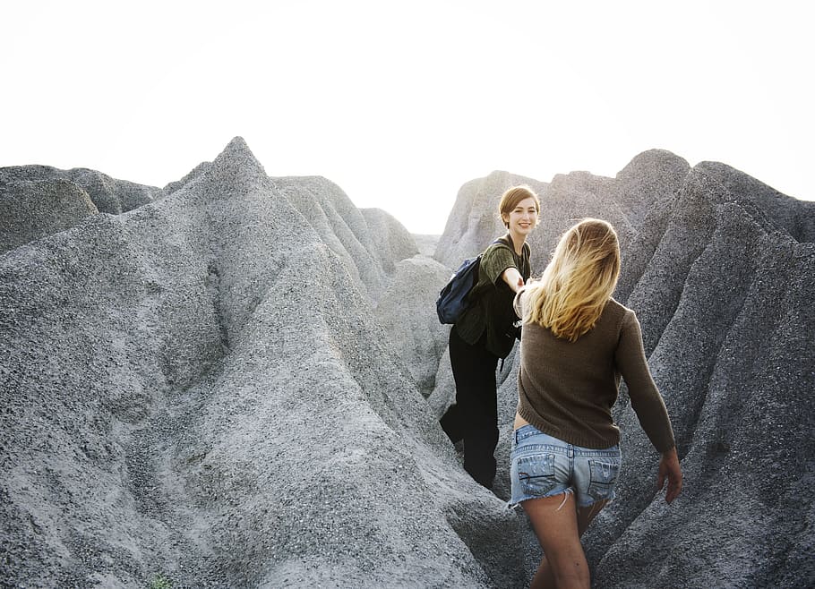 woman reaching other woman between rocks, active, adventure HD wallpaper