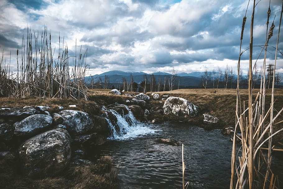 stream of water near brown soil and stone, river surrounded by brown grass under cloudy skies HD wallpaper