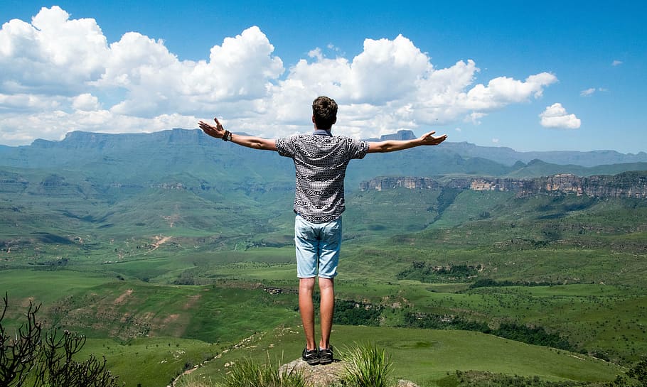 man in black shirt standing on cliff, clouds, landscape, mountain range HD wallpaper