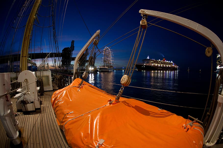 brown metal boat near the black and white cruise ship on water during nighttime, gray metal boat pulleys taken during night time HD wallpaper