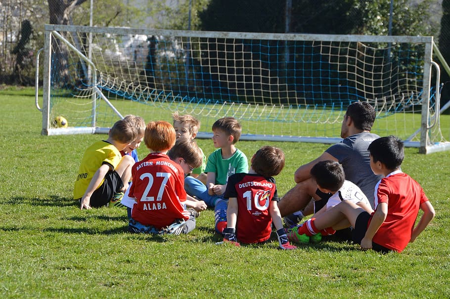 boys sitting on grass near soccer goal net, children, football
