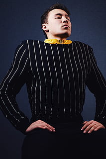 man doing sitting pose, man in black and white pinstripe long-sleeved top HD wallpaper