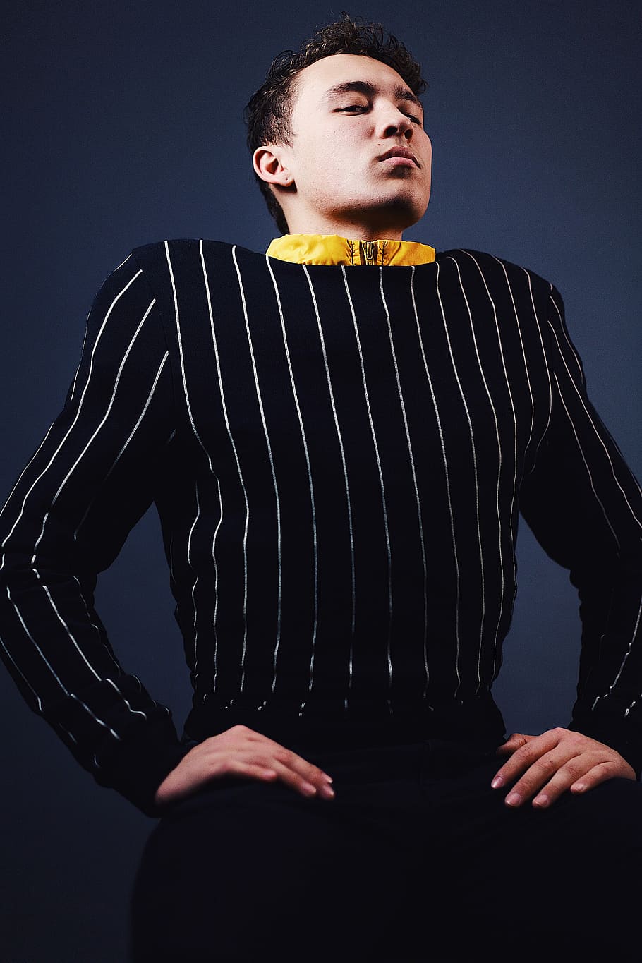 man doing sitting pose, man in black and white pinstripe long-sleeved top HD wallpaper