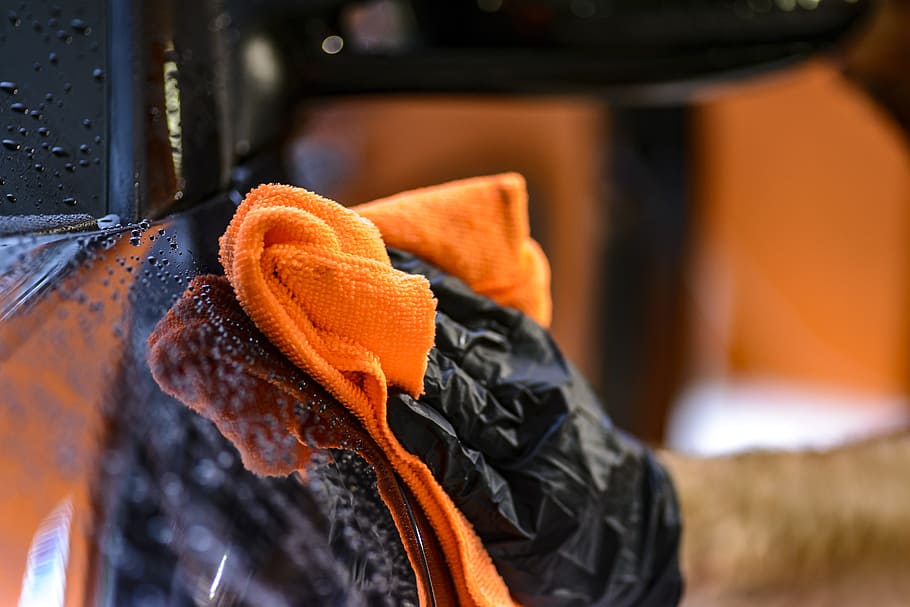 man wearing black gloves holding orange towel, cleaning, steam
