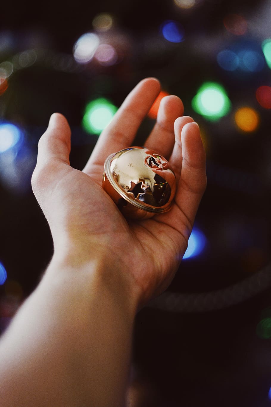 gold-colored bell, gold bauble on person's left palm, hand, holding HD wallpaper