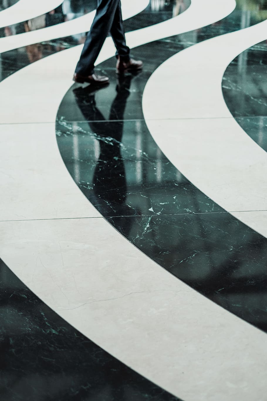 Swirling black and white pattern on a marble floor, person wearing black pants walking on white and black ceramic flooring HD wallpaper