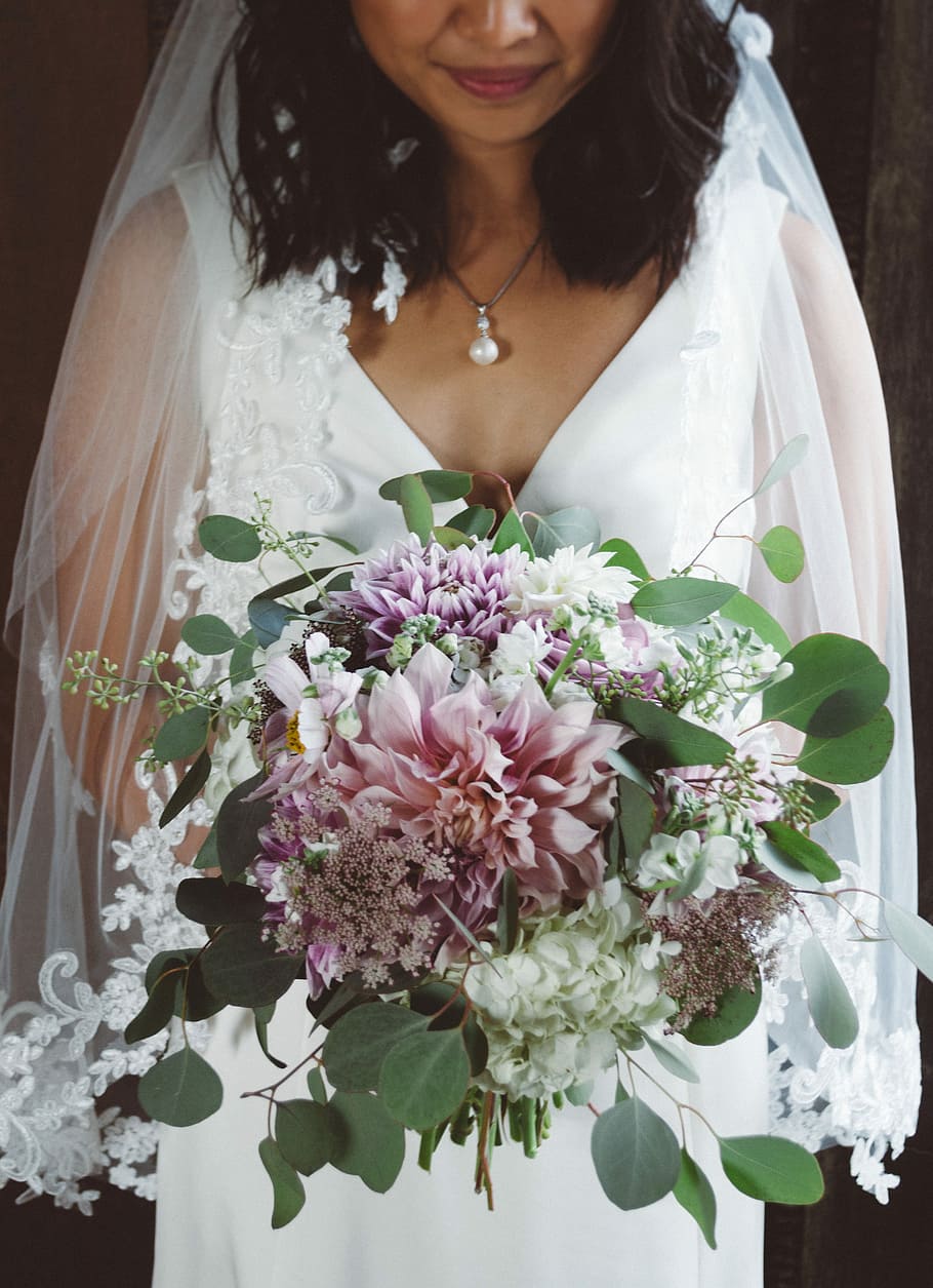 bride holding a bouquet of flower, woman wearing wedding gown and holding bouquet of flowers