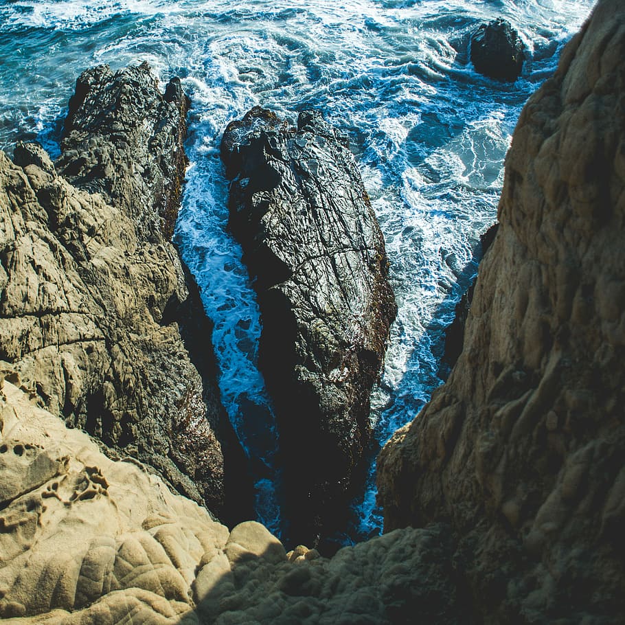 aerial photography of rock formations, rock formation near body of water during daytime HD wallpaper