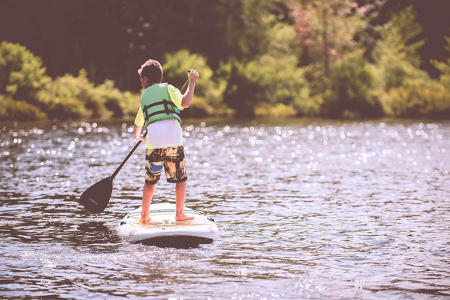 boy in green vest on white and black paddle boat on body of water during daytime HD wallpaper