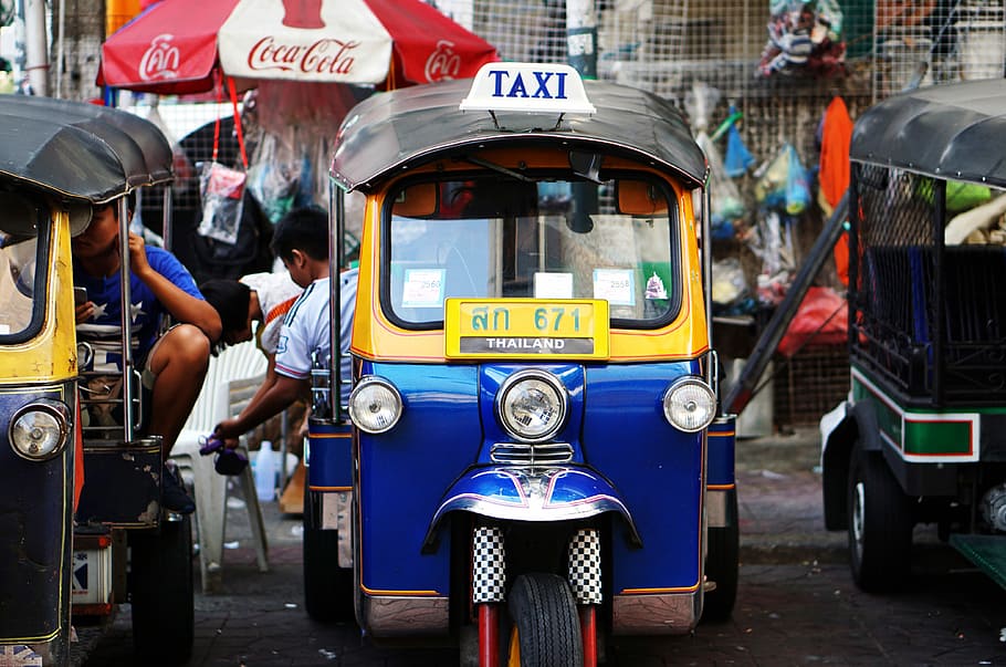 yellow and blue auto rickshaw parked beside auto rickshaw, blue and yellow auto rickshaw taxi on parked on black asphalt flooring