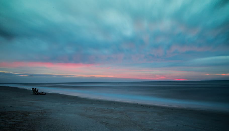 beach with drift wood, person sitting on gray sand near sea during dawn, HD wallpaper