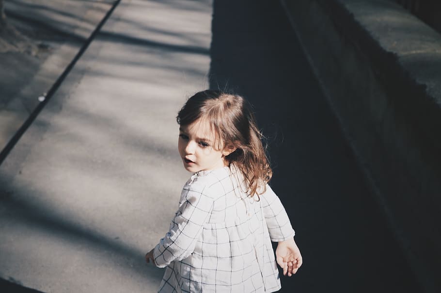 toddler girl walking on gray concrete road at daytime, girl wearing white jacket while looking her backside, HD wallpaper