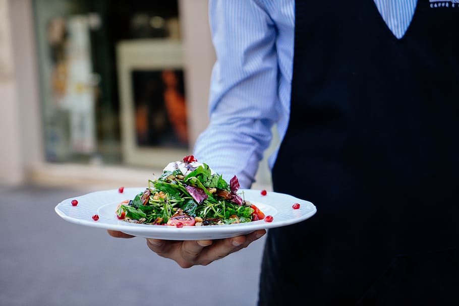person holding a plate of salad, waiter holding salad platter