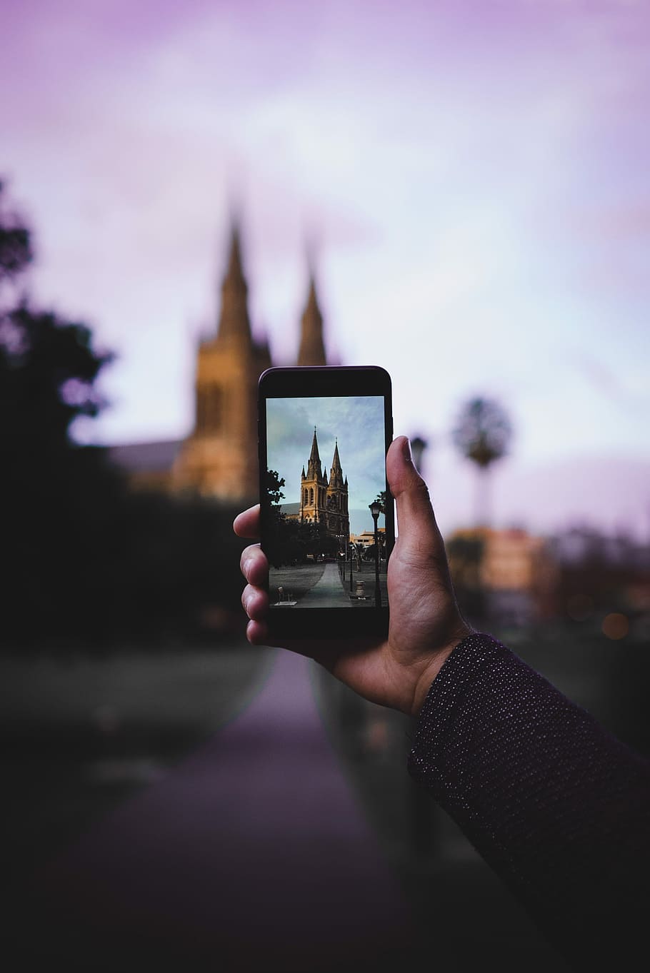 selective focus photography of person holding smartphone, person holding black smartphone while taking a picture of brown castle during daytime HD wallpaper
