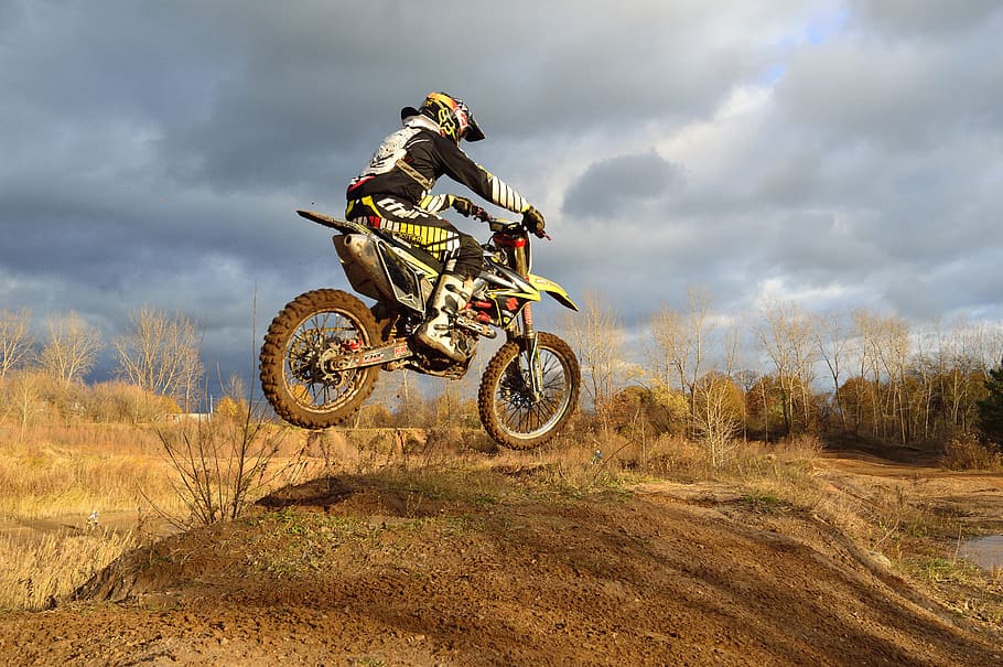 man in black and yellow motocross costume riding black and yellow motocross dirt bike doing stunt during daytime, HD wallpaper