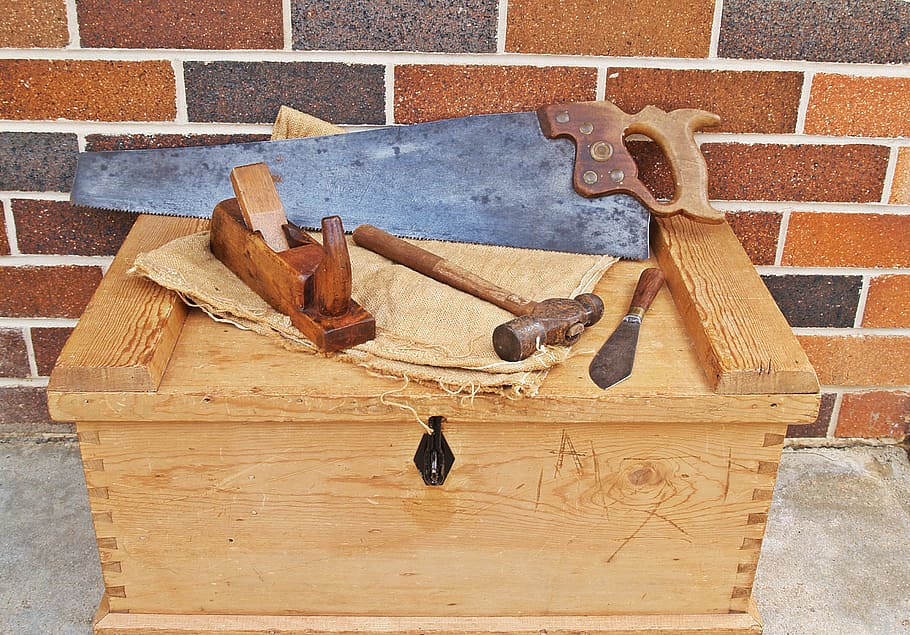 assorted hand tools on top of brown wooden box, carpenter's toolbox