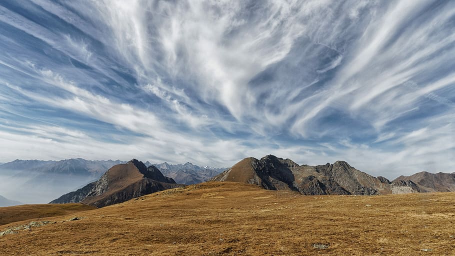 brown cliff with ocean in distance, barren land formation near body of water under white clouds HD wallpaper