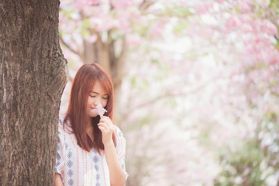 woman smelling flower beside tree, nature, trees, trunk, flowers HD wallpaper