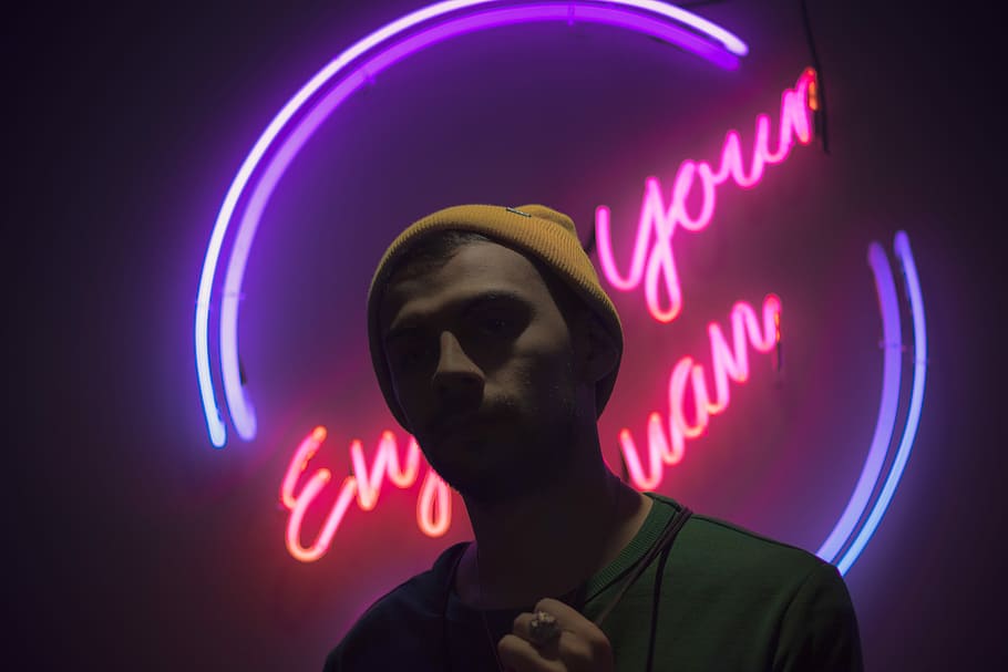 man standing in front of neon light signge, man standing in front of LED signage