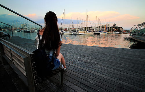 Woman in Black and White Stripe Scoop Neck Shirt Sitting on Brown Wooden Bench in Ship Dock during Daytime HD wallpaper